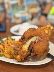 Golden crispy German pork knuckle (Schweinshaxe or Eisbein), a succulent and hearty dish with crackling skin and tender meat, served with roasted potatoes and salad. A popular Western-style  food.