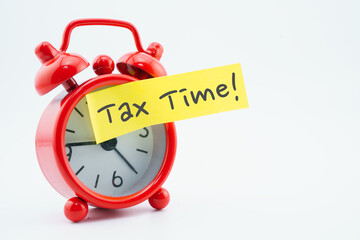 Tax time reminder sticky note on red alarm clock on white with copy space.
