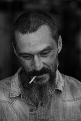 Black and white portrait of a handsome and optimistic nomad, bearded and smoking