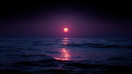 Sun or moon over dark ocean water reflecting light on the surface.