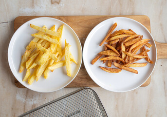 Two plates of fried french fries: one with crispy fries and one with soft, dark fries