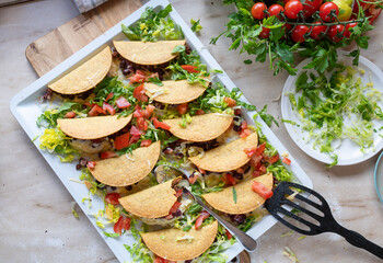 Oven baked tacos with minced meat, kidney bean, cheese filling on a baking tray fresh and homemade...