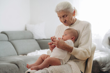 Holding toddler in hands. Grandmother with cute toddler baby at home