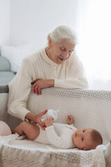 Taking care of toddler that is lying down. Grandmother with cute toddler baby at home
