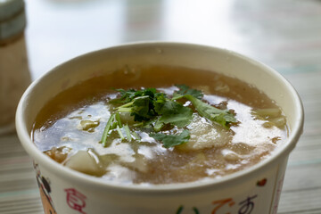 A steaming bowl of Taiwanese Spanish mackerel thick soup, filled with golden-brown fried fish chunks, served in a flavorful, slightly starchy broth. Garnished with shredded cabbage, cilantro, and a da