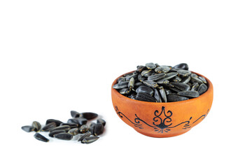 Heap of sunflower seeds in clay bowl isolated on white background.