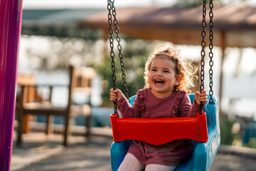 portrait of a adorable little girl laughing when playing a swing