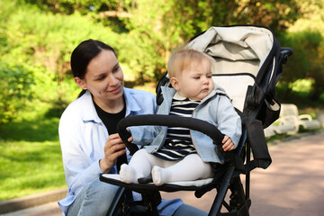 Mother with her cute baby in stroller at park