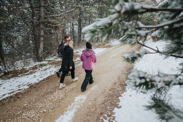 Outdoor winter scene of three people hiking along a snowy trail in a forest, exemplifying nature,...
