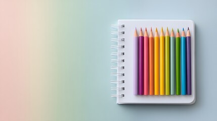 Fototapeta premium Colorful Pencils on White Spiral Notebook: Artistic Inspiration and Creative Stationery