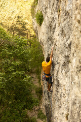 A man in a yellow shirt is climbing a rock wall