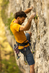 A man in a yellow shirt is climbing a rock wall