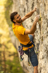 A man in a yellow shirt is climbing a rock wall