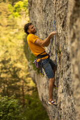 A man in a yellow shirt is climbing a rock wall