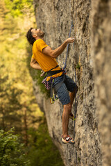 A man in a yellow shirt is climbing a rock wall