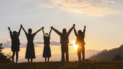 Five little girls are holding hands up and watching the sunset on mountain