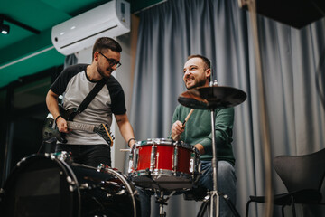 Two friends play drums and electric guitar in a fun and creative jam session. They enjoy making...