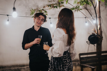 Two friends share a moment outdoors during a relaxed celebration under ambient lighting.