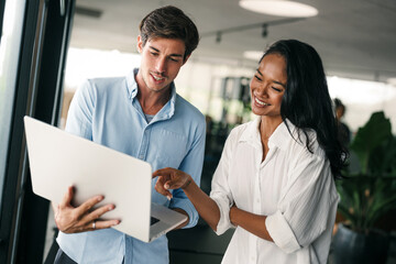 Two happy diverse multiethnic business team people working, talking in corporate office