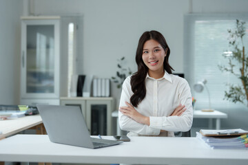 Asian businesswoman smiling with crossed arms in office