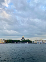 Fototapeta premium Scenic view of a classical domed building surrounded by trees and waterfront under dramatic sky