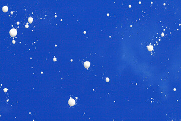Fototapeta premium Small white droplets scatter across vibrant ultramarine field in chaotic arrangement.