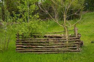 Natural wooden compost bin with rustic woven fence and growing young trees in eco-friendly garden...