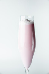 A tall glass with a frothy pink smoothie against a clean white background. The drink’s creamy texture and vibrant color make it look refreshing and inviting, perfect for summer or dessert concepts