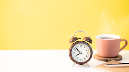 classic alarm clock and a cup of coffee on stacked books illustrating time management, work and education focus