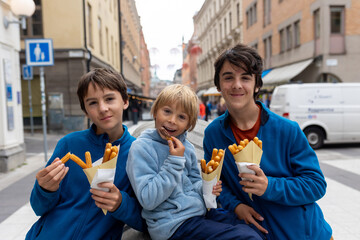 Cute blond child, eating churros on the street in the city of Stockhlom, sweet desert sold on every corner