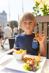Family with children, having lunch in a restaurant in Coppenhagen, eating local fish and lobster thermidor with salad and fries