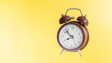 classic chocolate alarm clock isolated on yellow background