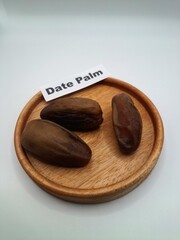 Date palm fruit on a small wooden plate. Dates are fruits from the date palm tree, chewy and sweet