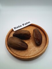 Date palm fruit on a small wooden plate. Date palm fruits, or simply dates, are the oval-shaped, sweet, edible fruit of the date palm tree (Phoenix dactylifera)