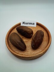 Date palm fruit on a small wooden plate. Date palm fruits, or simply dates, are the oval-shaped, sweet, edible fruit of the date palm tree (Phoenix dactylifera)