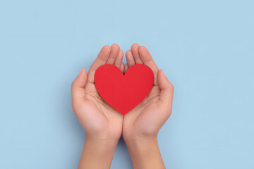 Hands Holding a Paper Red Heart Shape Top view Isolated On Blue Backdrop
