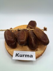 Date palm fruit on a on a round wooden board. Date palm fruits, or simply dates, are the oval-shaped, sweet, edible fruit of the date palm tree (Phoenix dactylifera)
