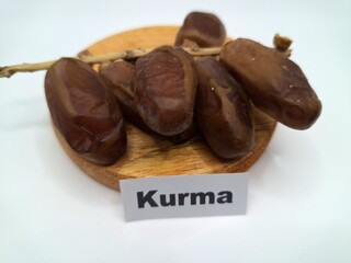 Date palm fruit on a on a round wooden board. Date palm fruits, or simply dates, are the oval-shaped, sweet, edible fruit of the date palm tree (Phoenix dactylifera)