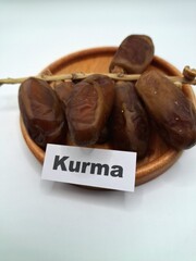 Date palm fruit on a small wooden plate. Date palm fruits, or simply dates, are the oval-shaped, sweet, edible fruit of the date palm tree (Phoenix dactylifera)