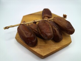 Date palm fruit on wooden serving board. Date palm fruits, or simply dates, are the oval-shaped, sweet, edible fruit of the date palm tree (Phoenix dactylifera)
