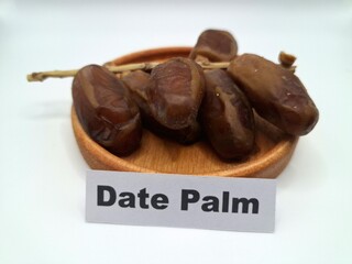 Date palm fruit on a small wooden plate. Date palm fruits, or simply dates, are the oval-shaped, sweet, edible fruit of the date palm tree (Phoenix dactylifera)