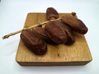 Date palm fruit on wooden serving board. Date palm fruits, or simply dates, are the oval-shaped, sweet, edible fruit of the date palm tree (Phoenix dactylifera)