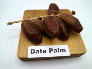 Date palm fruit on wooden serving board. Date palm fruits, or simply dates, are the oval-shaped, sweet, edible fruit of the date palm tree (Phoenix dactylifera)