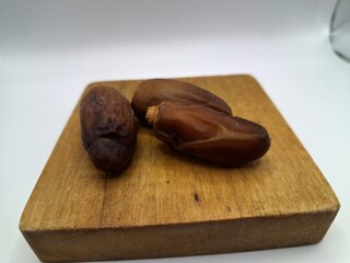 Date palm fruit on wooden serving board. Date palm fruits, or simply dates, are the oval-shaped, sweet, edible fruit of the date palm tree (Phoenix dactylifera)