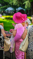 Woman in bright pink outfit with shopping bags buying summer jewelry in city market. Concept of street fashion, street shopping, street lifestyle