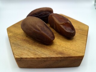 Date palm fruit on wooden serving board. Date palm fruits, or simply dates, are the oval-shaped, sweet, edible fruit of the date palm tree (Phoenix dactylifera)