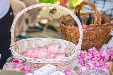 Handmade pink soap roses and natural cosmetics arranged in wicker baskets at outdoor artisan market. Concept of floral skincare, handmade gifts, natural self-care