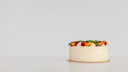 Side of a creamy cake with whipped cream and fruits.