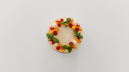 Top of a creamy cake with whipped cream and fruits.