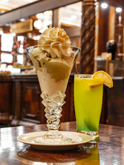 Ice cream sundae in a tall decorative glass with lemonade.